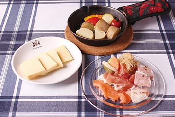10 種のチーズプレート 前菜盛り合わせ ラクレットチーズとジャガイモなどがテーブルに並べられている
