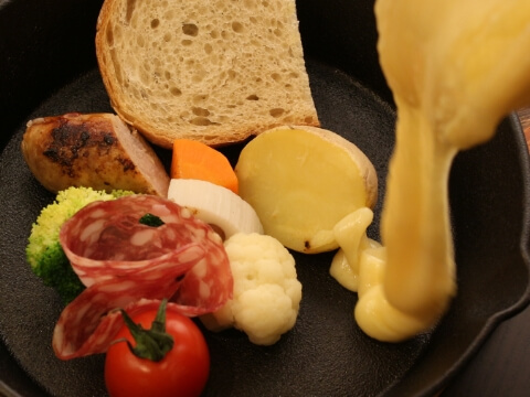 ジャガイモやパンに溶けたチーズをかけている